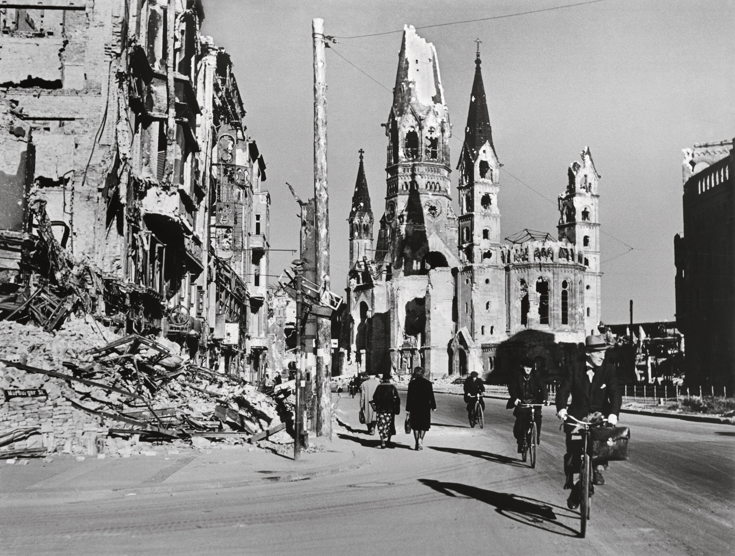 Robert Capa Gente lungo una strada fiancheggiata da edifici distrutti Berlino, Germania, agosto 1945 © Robert Capa © International Center of Photography_Magnum Photos